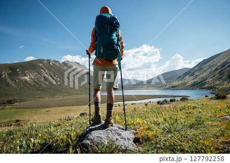 Woman backpacker hiking on high altitude mountain top,with a lake in the distance 127792258
