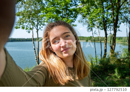 A Young Woman Happily Enjoying Nature by the Peaceful Lake in Beautiful Sunny Weather A Young Woman Happily Enjoying Nature by the Peaceful Lake in Beautiful Sunny Weather 127792510