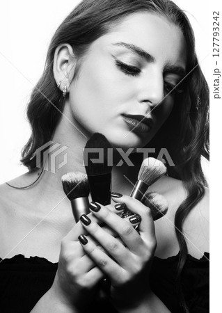 Beautiful woman with make-up brushes and closed eyes studio portrait 127793242