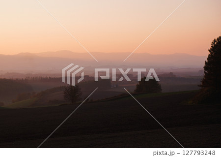 朝靄に包まれる丘と森の風景 127793248