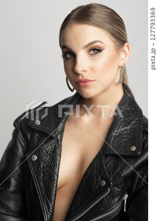 Woman studio portrait with black punk leather jacket and without bra 127793369