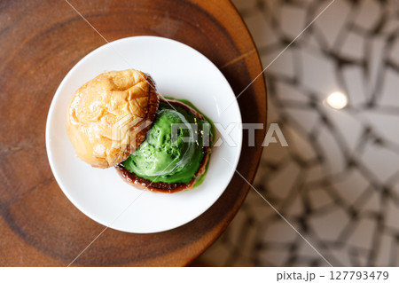 Scoop of Matcha green tea ice cream with bun bread on wooden table. 127793479