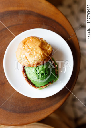 Scoop of Matcha green tea ice cream with bun bread on wooden table. 127793480