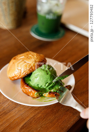 Scoop of Matcha green tea ice cream with bun bread on wooden table. 127793482