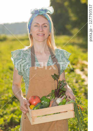 Portrait of beautiful woman picking up vegetables in garden 127793537