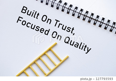 Built On Trust Focused On Quality on notebook with miniature ladder on table Built On Trust Focused On Quality on notebook with miniature ladder on table 127793593