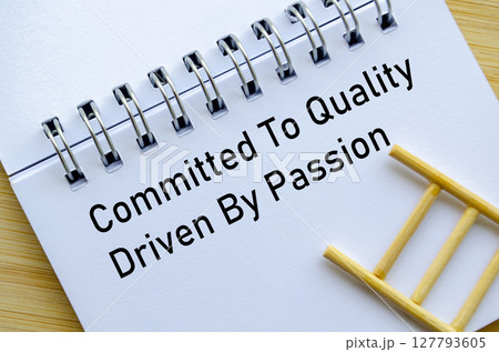 Committed To Quality Driven To Deliver Message On Notebook With Miniature Ladder On Wooden Surface 127793605