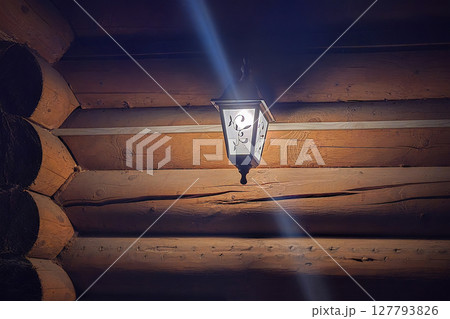 Lantern on a log wall. 127793826
