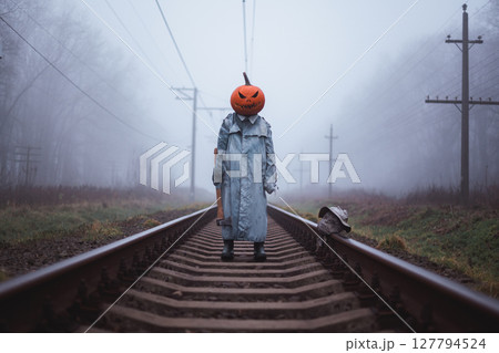 Terrifying person in carved pumpkin mask with axe Terrifying person in carved pumpkin mask with axe 127794524