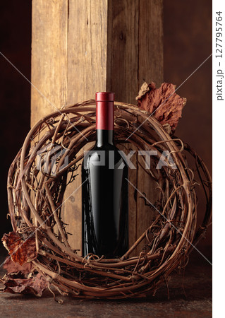 Bottle of red wine and dried grapevine wreath. 127795764