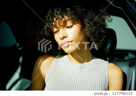 A woman with curly hair is sleeping in a car 127796132