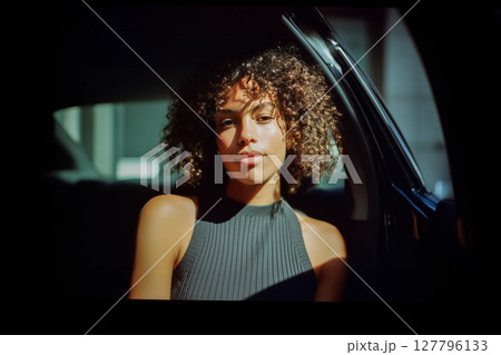 A woman with curly hair is sitting in a car 127796133