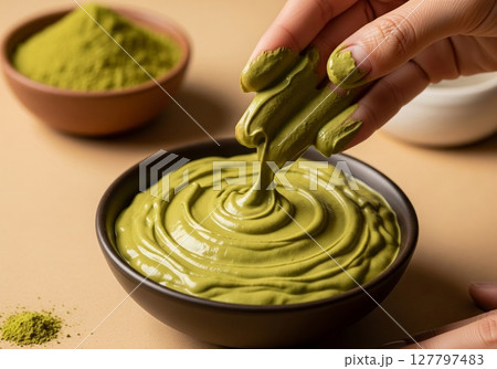 Artisan Hands Creating Luxurious Matcha Green Tea Skincare Mask in Ceramic Bowl 127797483