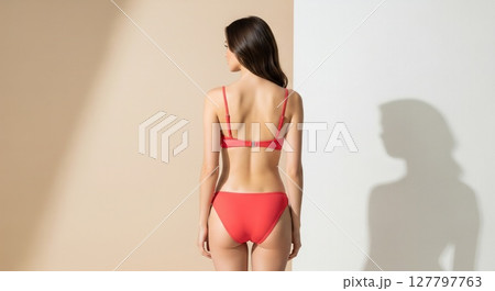 Elegant Red Bikini Fashion Model Poses Against Minimalist Studio Background 127797763