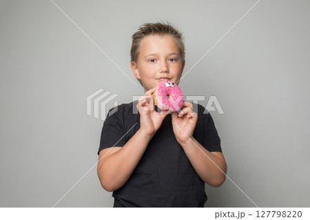 Cute child boy holding testy donut. Kid in black t-shirt with sweet food indoor Cute child boy holding testy donut. Kid in black t-shirt with sweet food indoor 127798220