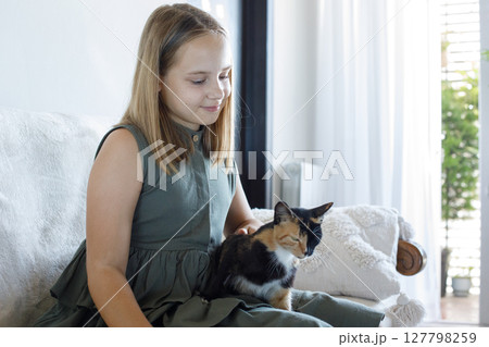 Cute friends. Young child girl with her cat pet companion indoor Cute friends. Young child girl with her cat pet companion indoor 127798259