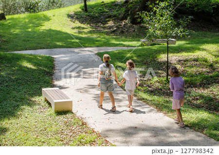 Little children walking in park outdoors. Happy young girl friends 127798342