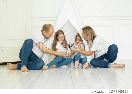 Smiling family having fun with puppy dog pet at home Smiling family having fun with puppy dog pet at home 127798433