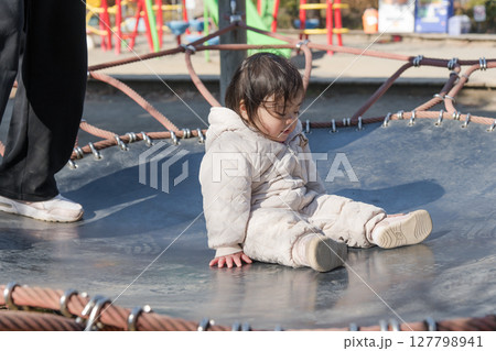 【相模原市立麻溝公園の子どもの広場のトランポリンでママと遊ぶ1歳児】 127798941