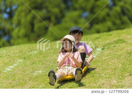 ソリで草すべりをする子どもたち ソリで草すべりをする子どもたち 127799208