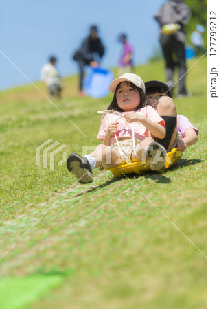 ソリで草すべりをする子どもたち ソリで草すべりをする子どもたち 127799212