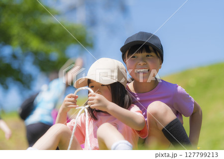 ソリで草すべりをする子どもたち 127799213