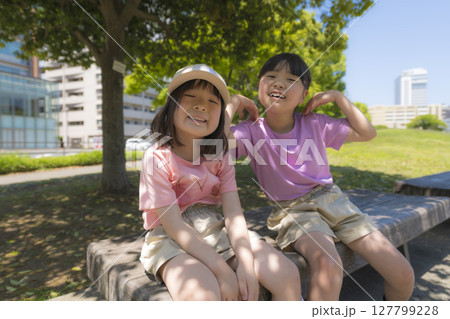 公園のベンチで笑顔を見せる姉妹の夏のひととき 公園のベンチで笑顔を見せる姉妹の夏のひととき 127799228
