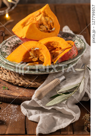 Sliced hokkaido pumpkin on a wooden board. Autumn cozy cooking concept Sliced hokkaido pumpkin on a wooden board. Autumn cozy cooking concept 127799857