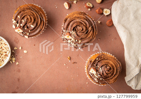 Chocolate chip muffins decorated with chocolate ganache and hazelnut 127799959