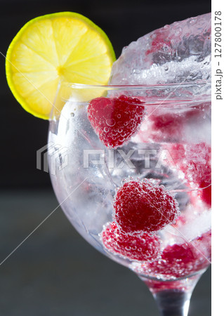 Gin tonic cocktail with raspberry and ice macro closeup 127800178