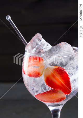Gin tonic cocktail with strawberries ice macro closeup 127800179