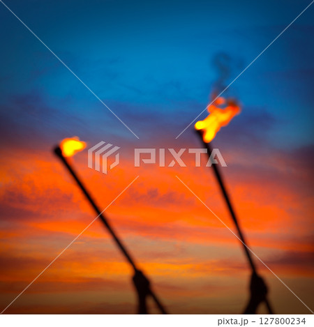 Fire torch at sunset sky with red clouds Fire torch at sunset sky with red clouds 127800234