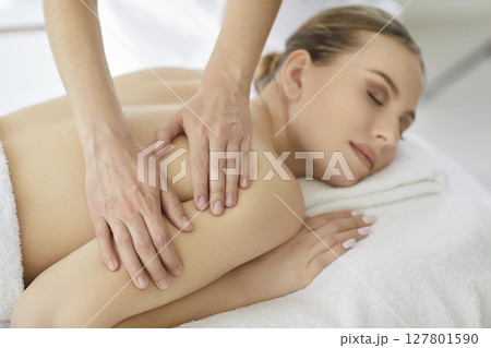 Massage therapist doing relaxing back, neck and shoulders massage treatment for woman 127801590