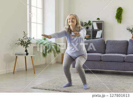 Squat exercise of senior woman training at home,old happy lady with arms stretching forward Squat exercise of senior woman training at home,old happy lady with arms stretching forward 127801613