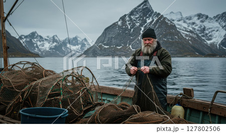 Nordic Fisherman Mending Nets on a Boat with Snowy Mountain Backdrop in Norway 127802506