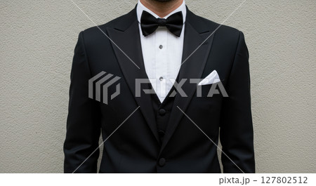Close-Up of Man Wearing Elegant Black Tuxedo and Bow Tie with White Pocket Square 127802512