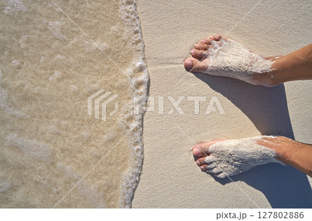 Caribbean tourist male feet on white sand shore 127802886