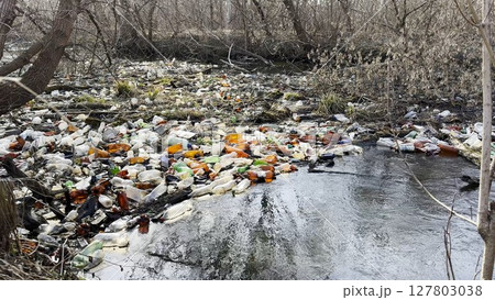 Dirty river is polluted with many plastic bottles. A lot of trash is dumped in open and freely available places at nature. Global environmental pollution problem. Concept of ecological disaster Dirty river is polluted with many plastic bottles. A lot of trash is dumped in open and freely available places at nature. Global environmental pollution problem. Concept of ecological disaster 127803038
