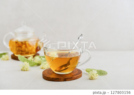 Glass cup of linden tea with glass teapot 127803156