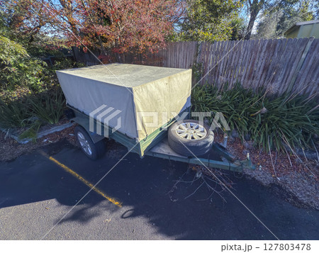 An old rusty trailer stored in a small community carpark 127803478