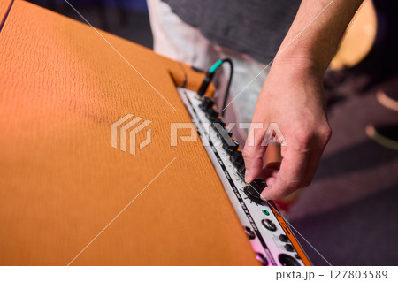 A musician is adjusting the amplifier on stage during a live performance for dynamic sound A musician is adjusting the amplifier on stage during a live performance for dynamic sound 127803589