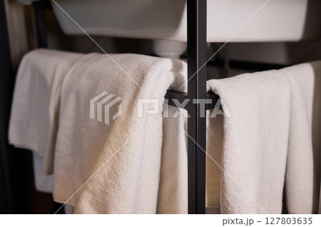 Elegant White Towels Neatly Displayed on a Stylish Modern Rack for a Sophisticated Touch 127803635