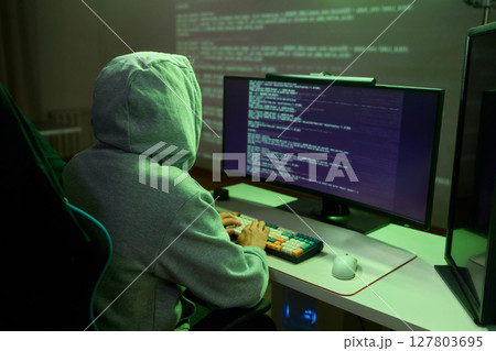 A young programmer codes intently in a dark setting, immersed in his work and creativity 127803695
