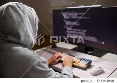 A young programmer codes intently in a dark setting, immersed in his work and creativity 127803696