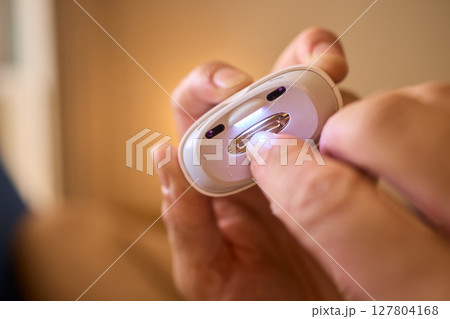 Close-up of an electric nail clipper in hand, modern personal care technology, highlighting compact design and functionality, modern gadget for personal grooming Close-up of an electric nail clipper in hand, modern personal care technology, highlighting compact design and functionality, modern gadget for personal grooming 127804168