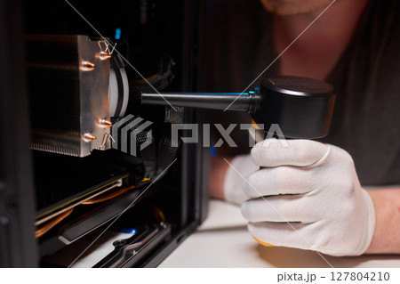 A man cleans a computer case with a vacuum in a bright room, stressing workspace tidiness A man cleans a computer case with a vacuum in a bright room, stressing workspace tidiness 127804210