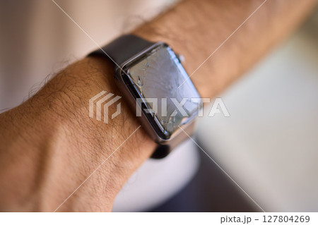 Closeup view of a Smartwatch resting on a Wrist featuring noticeable Scratches and marks 127804269
