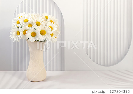 Beautiful daisy flowers in vase on elegant modern background, spring and summer product advertising banner, abstract floral arrangement, holiday greeting card with space for text Beautiful daisy flowers in vase on elegant modern background, spring and summer product advertising banner, abstract floral arrangement, holiday greeting card with space for text 127804356