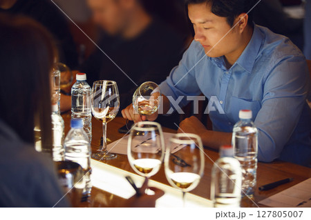 Asian Sommelier Tasting Wine at Table During Training 127805007