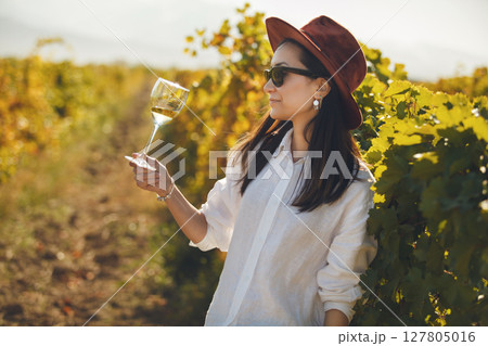 Woman in Hat and Sunglasses Holding Glass of Wine 127805016